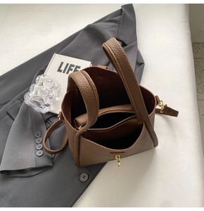 Macro view of brown lychee leather bucket bag showing inner liner and gold metal clasp