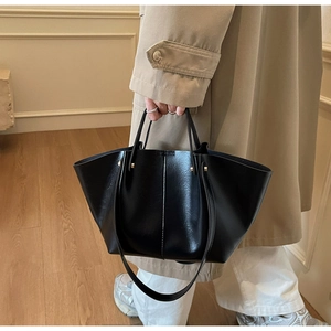 Gros plan du sac cabas en cuir noir avec clous dorés et doubles poignées de transport
