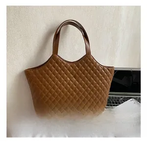 Close-up of brown quilted leather tote bag with gold clover clasp on office desk