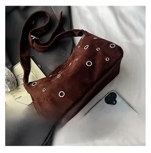 Détail du sac à bandoulière en daim marron foncé avec œillets métalliques argentés