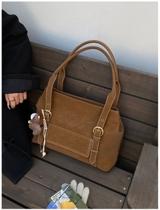 Détail d'un cabas en daim marron avec surpiqûres blanches et porte-clé petit ours