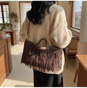 Détails du sac cabas marron vintage montrant les longues franges en daim et lanières