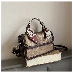 Detail of metallic brown mini bag with leather trim and decorative patterned silk scarf