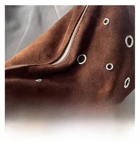 Détail macro du sac en daim marron foncé avec fermetures éclair et œillets argentés