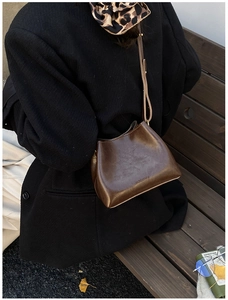 Nahaufnahme einer braunen Vintage-Eimertasche aus Leder im herbstlichen Stil