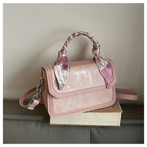 Pink crossbody bag with pearlescent texture and floral scarf wrapped on the handle