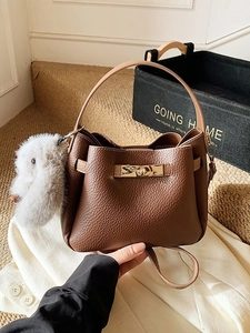 Retro brown lychee leather bucket bag with gold clasp and plush rabbit pendant decor