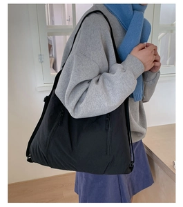 Détail d'un grand sac cabas noir avec fermeture éclair verticale pratique et bandoulière solide