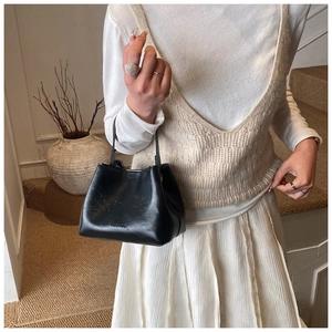 Schwarze glänzende Eimertasche aus Leder mit Henkeln in gemütlichem Wohnambiente
