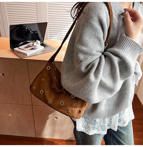 Gros plan d'un sac cabas en daim marron avec œillets métalliques dans un bureau
