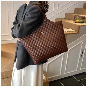 Detail of large brown quilted tote bag with gold clover logo for commuting