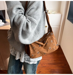 Détail du sac cabas en daim marron avec œillets métalliques argentés et fermeture éclair