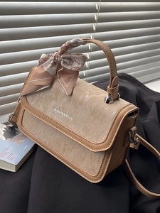 Chic beige corduroy handbag with leather trim and decorative scarf in natural lighting