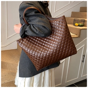 Brown quilted leather tote bag with diamond stitching shown on model shoulder