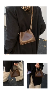 Detailaufnahme der dunkelbraunen Vintage-Eimertasche mit HOCOMU-Logo und Gurt