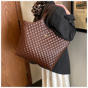 Detail of deep brown quilted faux leather tote bag with gold floral clasp for women