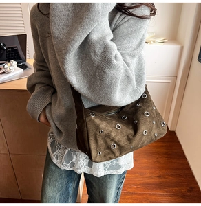 Détail d'un sac à bandoulière en daim marron foncé avec œillets et rivets métalliques