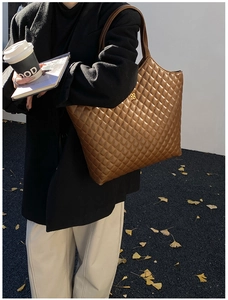 Brown quilted leather tote bag with gold floral logo and long strap in street style