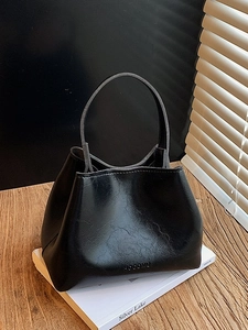 Elegante schwarze glänzende PU-Leder Eimertasche mit Tragegriff auf einem Holztisch