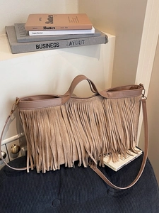 Sac cabas bohème en daim marron avec franges et bandoulière amovible sur un pouf bleu