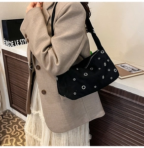 Gros plan du sac bandoulière en daim noir avec œillets métalliques et style industriel