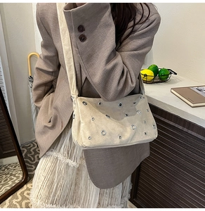 Détail du sac bandoulière en daim beige avec rivets ajourés et œillets métalliques