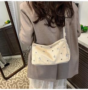 Détail du sac fourre-tout en daim beige avec œillets argentés et large bandoulière