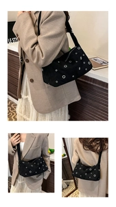 Détail d'un sac hobo en toile noire avec œillets métalliques et large bandoulière réglable