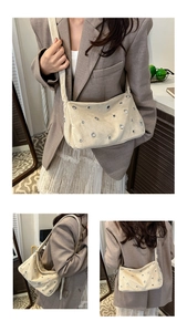Détail du sac baguette en daim beige avec œillets métalliques et bandoulière