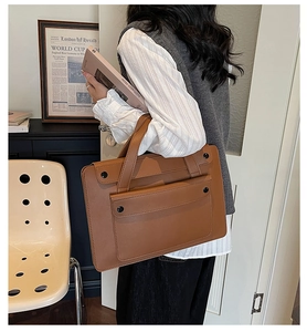Vista dettagliata della borsa porta PC in pelle marrone con tasca frontale e fibbie nere