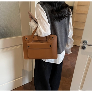 Borsa porta PC in pelle marrone indossata da un modello in un contesto professionale