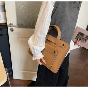 Valigetta porta PC classica in pelle color cammello con doppi manici in contesto professionale
