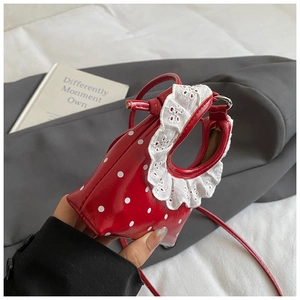 Detail of mini red polka dot handbag with elegant white lace trim and glossy finish