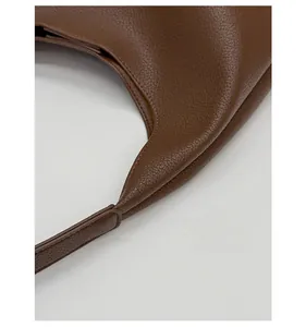 Detail of precision stitching on dark brown pebbled leather shoulder bag strap