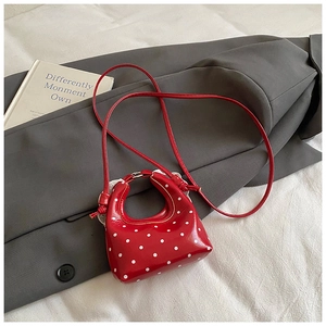 Chic red polka dot mini bag in glossy patent leather on a stylish gray blazer