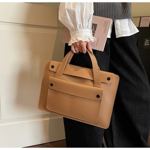 Dettaglio di una borsa da ufficio in pelle color cuoio con bottoni magnetici neri