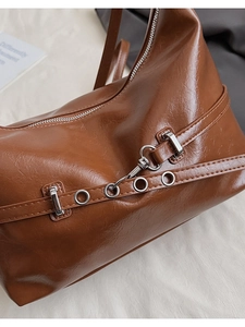 Gros plan sur la texture en cuir PU caramel et les détails métalliques du sac