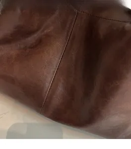 Gros plan sur la texture du cuir marron foncé et les coutures de ce sac cabas chic