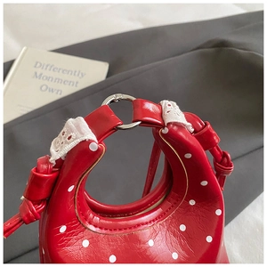 Detailed close-up of a red polka dot handbag featuring white lace trim and silver hardware