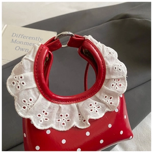 Close-up of red polka dot mini handbag with white lace embroidery and metal ring handle