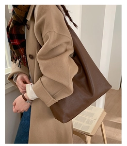 Brown leather tote bag styled with a wool coat and checkered scarf for a cozy look