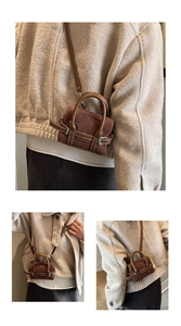 Details der braunen matten Mini-Handtasche mit Kontrastnähten und Textur im Fokus