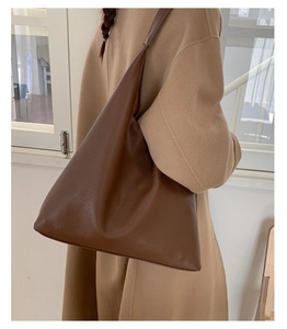 Detail of large brown pebble leather tote bag with wide strap on a model's shoulder