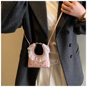 Detail of a pink mini crossbody bag with black polka dots and white lace trim