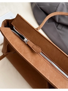 Gros plan sur la fermeture éclair en métal argenté d'un sac cabas en daim marron