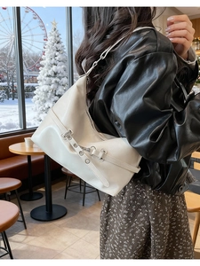 Détail du sac cabas en similicuir crème avec boucles métalliques dans un décor de café d'hiver