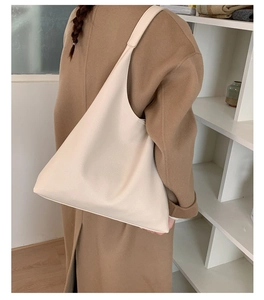 Close-up of minimalist off-white hobo tote bag with lychee texture and wide strap