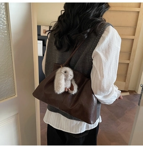 Détail d'un sac cabas en cuir marron foncé brillant avec un porte-clé lapin gris