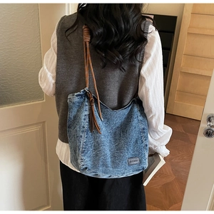 Detail of a large denim tote bag featuring durable washed fabric and brown braided straps