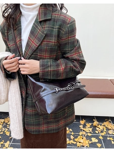 Détail du sac sous le bras marron foncé brillant avec ceintures à oillets en décor d'automne